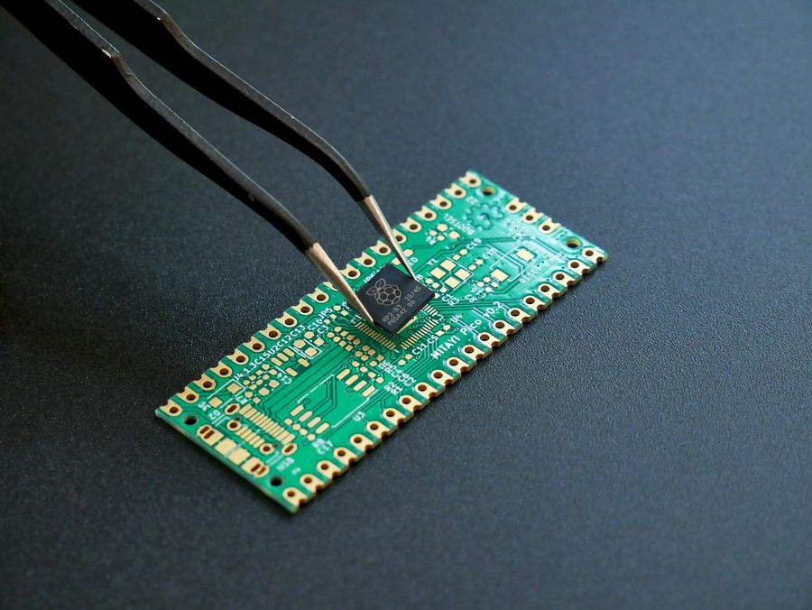 Pinza de precisión colocando un integrado sobre una placa